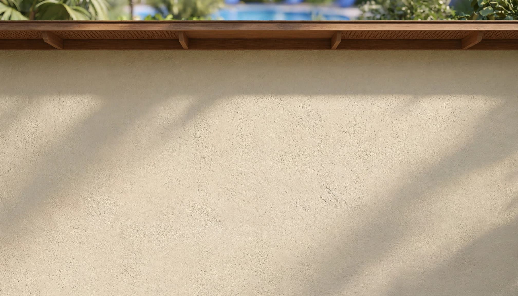 A repaired stucco wall dries beneath the eaves beside greenery.